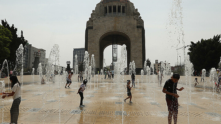 Personas juegan en una fuente del Monumento a la Revolución, en la Ciudad de México. 
