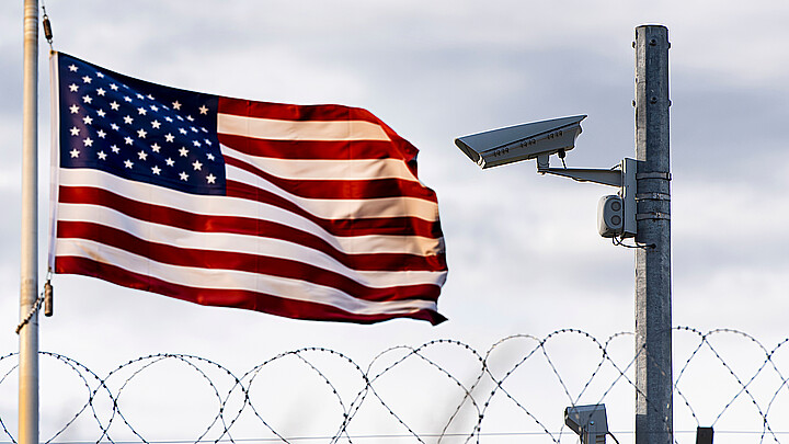 U.S. flag waving in the distance of barbed wire border 