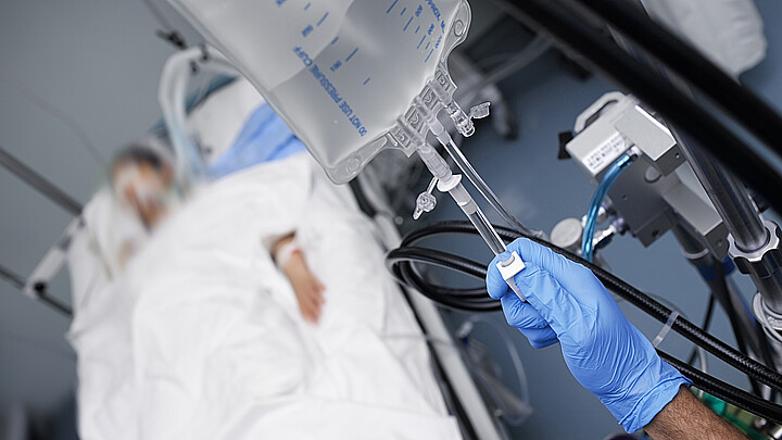 Una persona apaga el sistema de drogas intravenosas al paciente inconsciente.