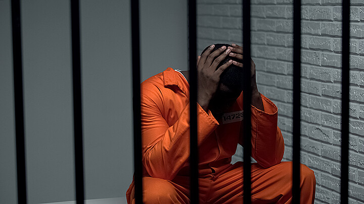 Desesperado prisionero sentado en una celda