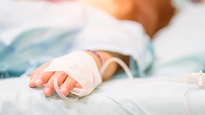 La mano estrecha del niño duerme en una cama en un hospital con enfoque selectivo e intravenoso salino