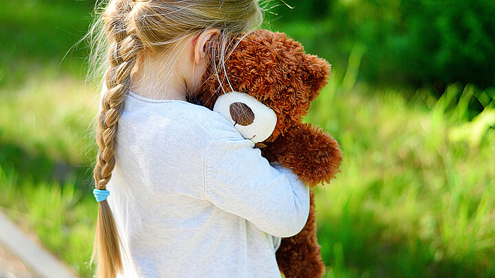 Niña abrazando oso de peluche