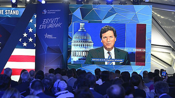 American media personality Tucker Carlson appears on the screen as he delivers his video message on the first day session of the Conservative Political Action Conference (CPAC) Hungary