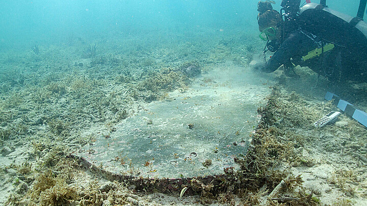 Estudiante graduado de la Universidad de Miami (UM), Devon Fogarty, examina una lápida encontrada bajo el agua por arqueólogos durante un estudio en el Parque Nacional Dry Tortugas 