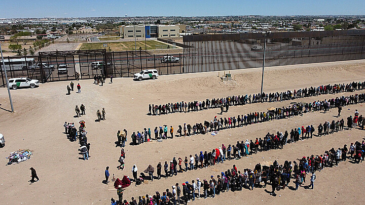 Fotografía de archivo de migrantes formados en la frontera de México y EE. UU.