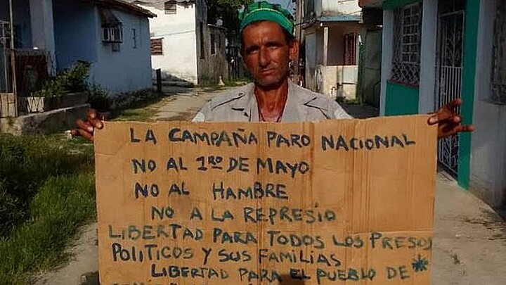 Trabajador cubano se manifiesta pacíficamente con un cartel en contra del régimen 