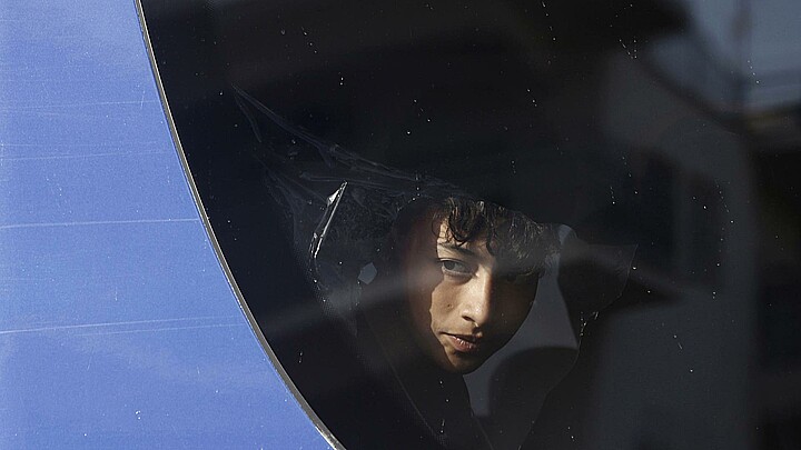 Un migrante rescatado del naufragio frente a las costas de Grecia se asoma a la ventanilla del autobus en el que es traladado a un centro de acogida