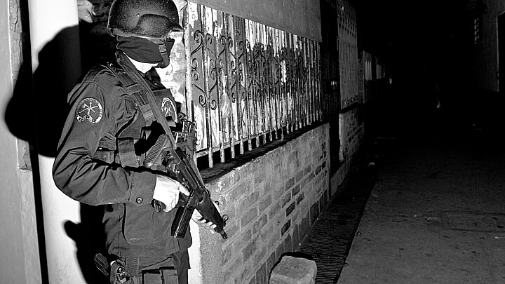 A Special Forces officer guards an alley during a raid against gang members