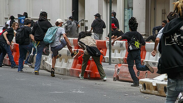 Varias personas derriban a patadas barreras de construcción durante los disturbios que se produjeron después de que un streamer intentara celebrar un sorteo en Nueva York