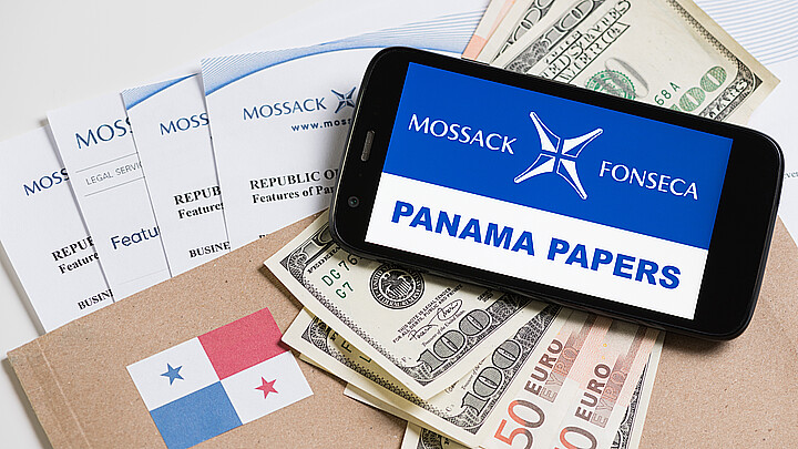Folder with Mossack Fonseca logo and printed documents from it's web site, Panama flag, U.S. and EU currency and phone with Panama Papers text