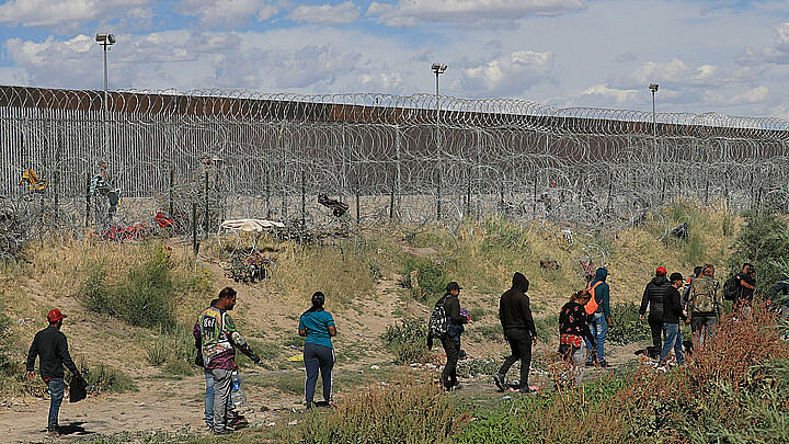 Migrantes caminan cerca del muro que separa la frontera estadounidense en Ciudad Juárez, Chihuahua (México). 