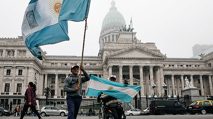 Personas sostienen banderas a las afueras del senado durante un debate