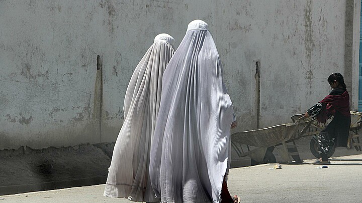 Fotografía de mujeres afganas vestidas con burka que caminan por una carretera en Kandahar, Afganistán. 