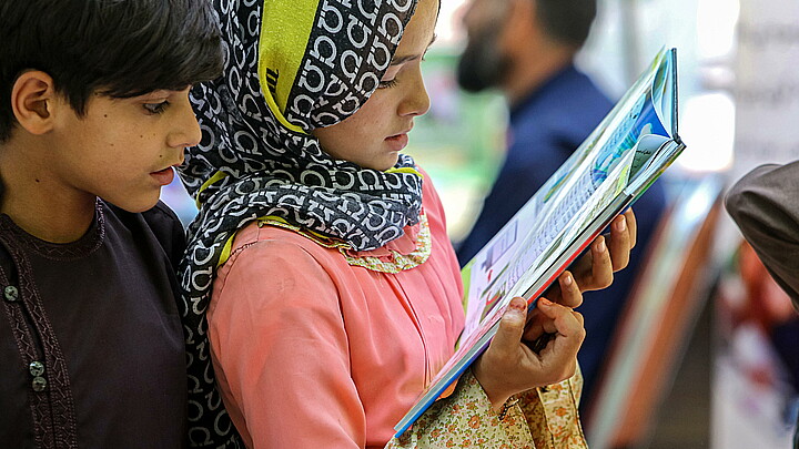 Children read a book as they visit a book exhibition in Kabul, Afghanistan, July 30, 2024