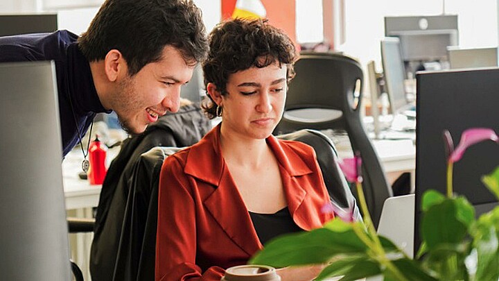 Pareja hablando al frente de un computador en una oficina