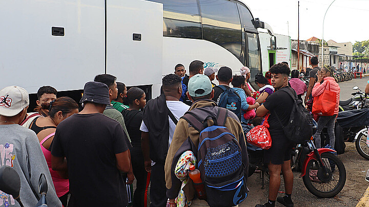 Migrantes hacen fila para abordar uno de los ocho autobuses del 'Corredor emergente de movilidad', en Tapachula (México). 