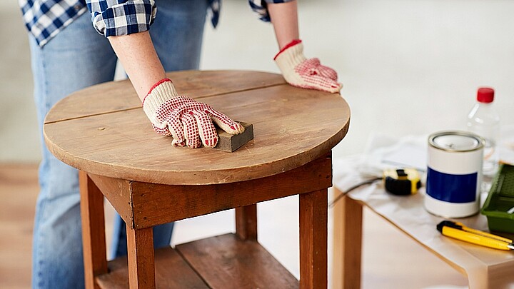 Primer plano de mujer lijando mesa de madera vieja con esponja