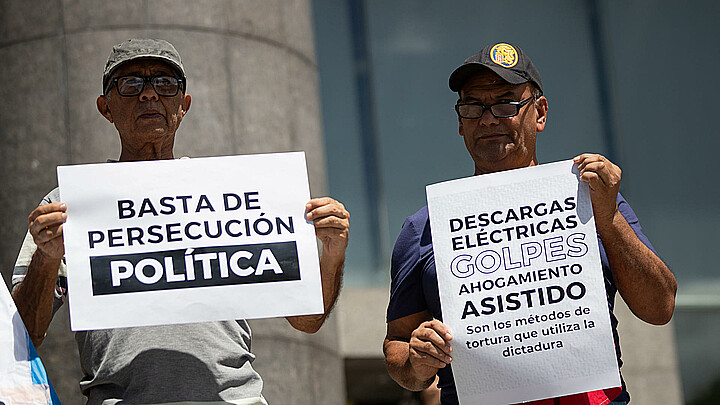 Personas sostienen carteles durante una manifestación frente a la sede de la ONU en Caracas (Venezuela). 