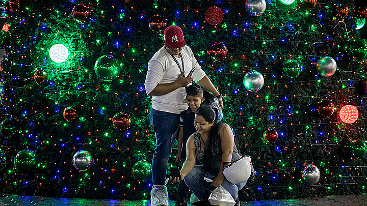 Personas se toman una fotografía junto a un árbol navideño, en Caracas (Venezuela). 