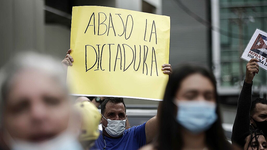 Hombre con cartel que denuncia la dictadura cubana