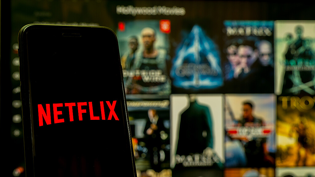 Hand holding martphone with logo Netflix on iphone