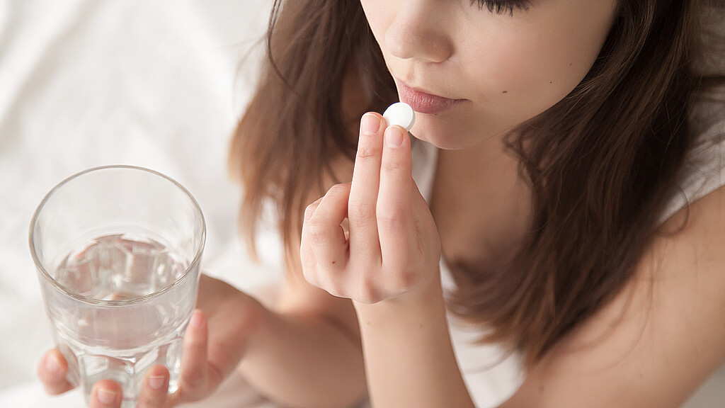 Stock image of young woman taking pill