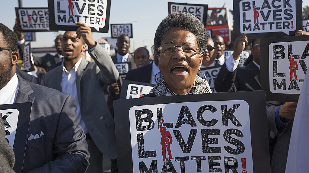 Mujer sostiene cartel "Black Lives Matter".
