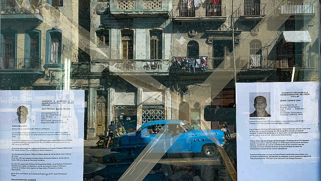 El reflejo de una calle de La Habana vieja, a través de una ventana que exhibe dos hojas de vida de delegados a diputados a la Asamblea del Poder Popular