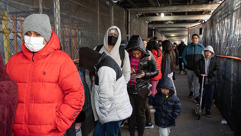 Asylum seekers wait online as Mayor Eric Adams helps distribute donated food and clothing to their families at public school 20 in New York on February 11, 2023