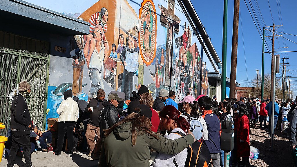 Inmigrantes esperan en una fila para recibir ayuda de alimentos y ropa cerca de un albergue