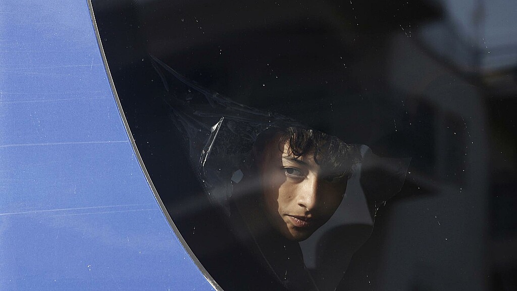 Un migrante rescatado del naufragio frente a las costas de Grecia se asoma a la ventanilla del autobus en el que es traladado a un centro de acogida