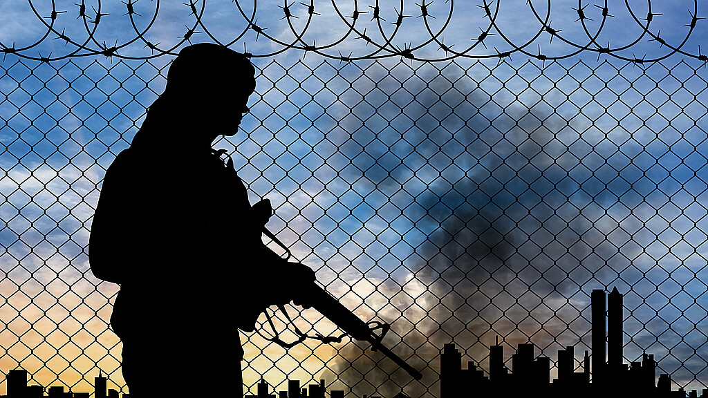 Silouhette of terrorism at border fence