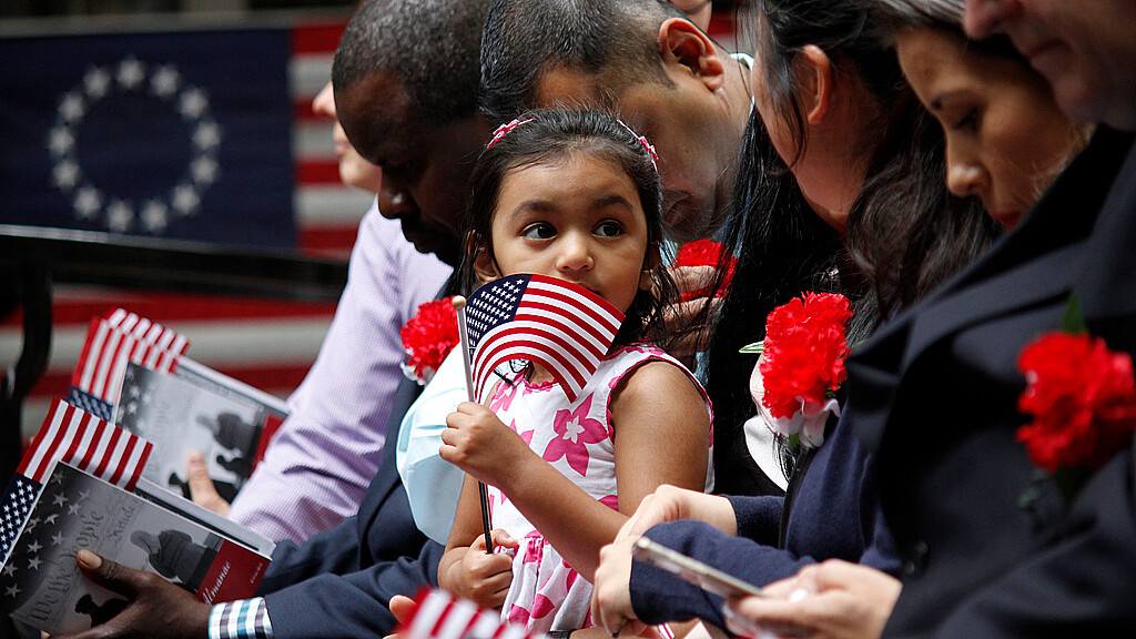 The daughter of an immigrant holds an American flag while she joins her mother's naturalization ceremony on Flag Day at the historic Betsy Ross House in Philadelphia