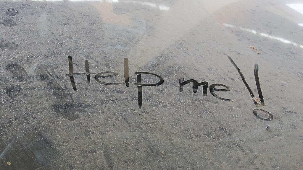 Mensaje de ayúdame escrito en la ventaja de un vehículo