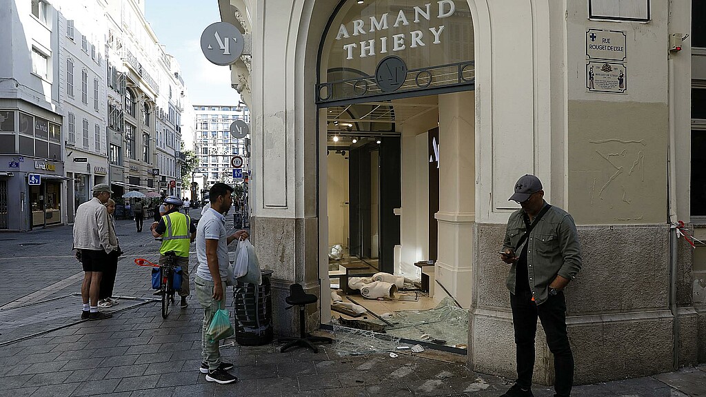 Varias personas ante una tienda dañada tras una noche de saqueos y disturbios en Marsella.