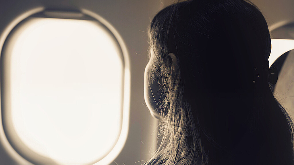 Mujer viendo por la ventana de un avión