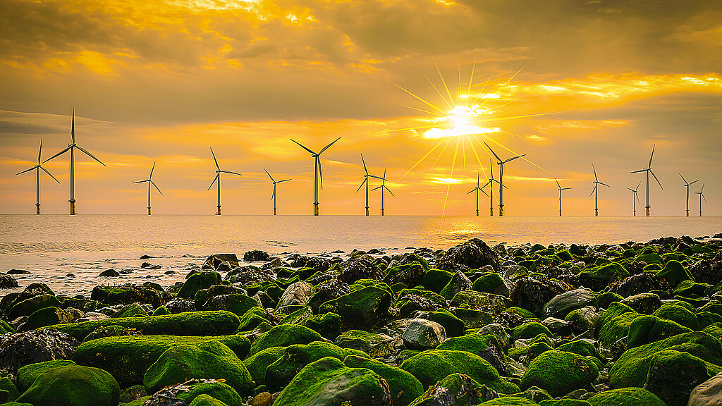 Offshore Wind Turbine in a Wind farm under construction off the England coast at sunset
