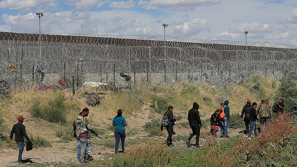 Migrantes caminan cerca del muro que separa la frontera estadounidense en Ciudad Juárez, Chihuahua (México). 