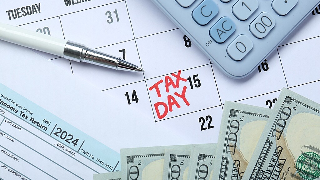 Calendario con dia de impuestos, una calculadora y seis billetes de 100 dólares