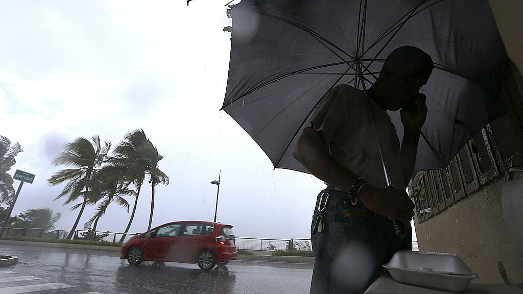 Un hombre camina bajo la lluvia en San Juan (Puerto Rico). Imagen de archivo. 