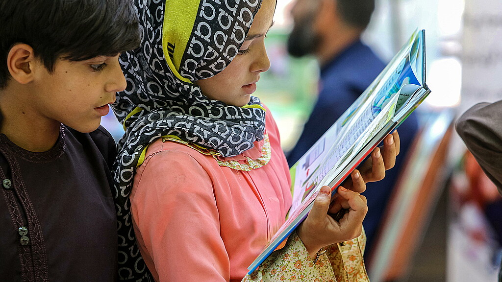 Children read a book as they visit a book exhibition in Kabul, Afghanistan, July 30, 2024