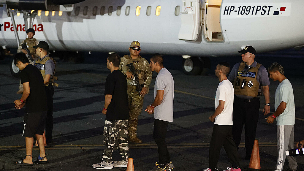 Migrantes esposados antes de ser deportados en el aeropuerto Marcos A. Gelabert en Ciudad de Panamá. 