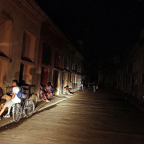 Varias personas conversan iluminadas por la luz de un automóvil en una calle del barrio El Cerro (La Habana) durante un apagón 