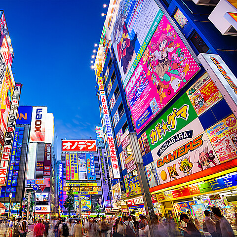 Crowds pass below colorful signs in Akihabara, Japan 