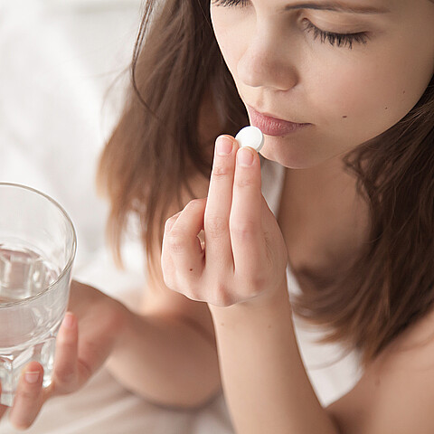 Stock image of young woman taking pill
