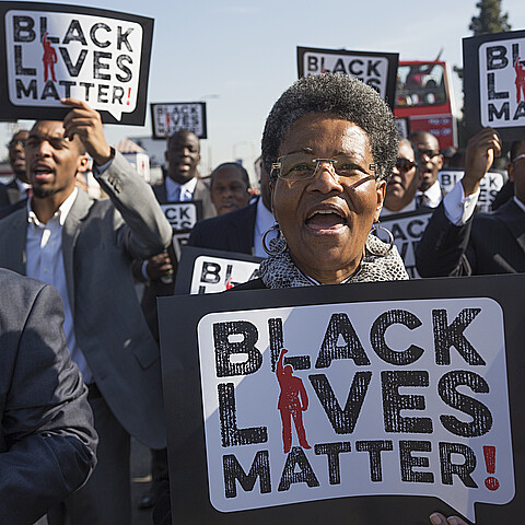 Mujer sostiene cartel "Black Lives Matter".