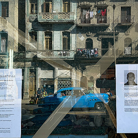 El reflejo de una calle de La Habana vieja, a través de una ventana que exhibe dos hojas de vida de delegados a diputados a la Asamblea del Poder Popular