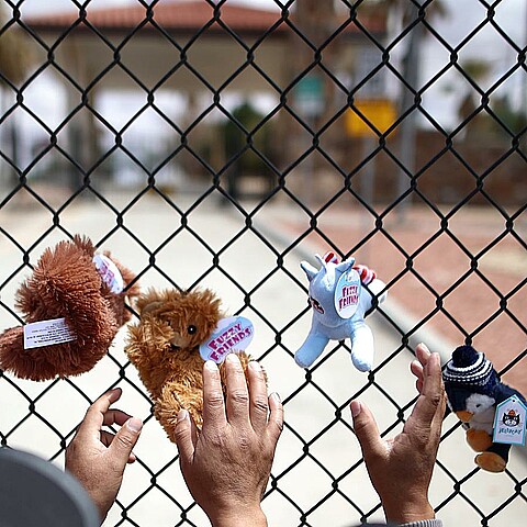 Fotografía de archivo de unas personas que cuelgan de manera simbólica unos muñecos de peluche como manera de representar la inocencia de los niños