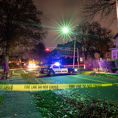 Escena del crimen con cinta adhesiva y patrulla de policía