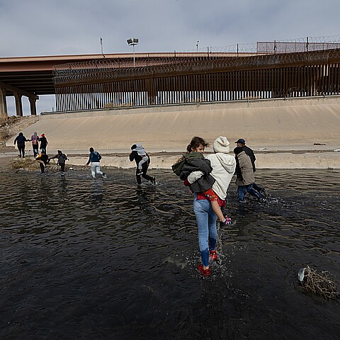 Grupo de migrantes cruzando la frontera de Río Bravo entre México y Estados Unidos